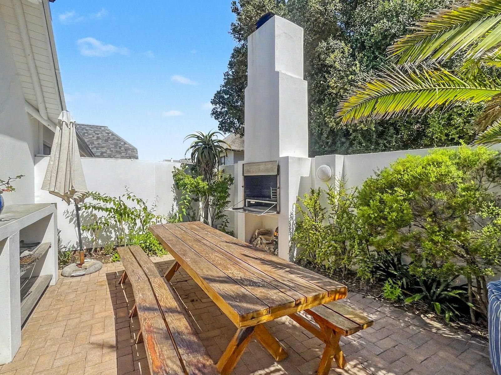 Brick-paved courtyard with built-in braai and a long timber table