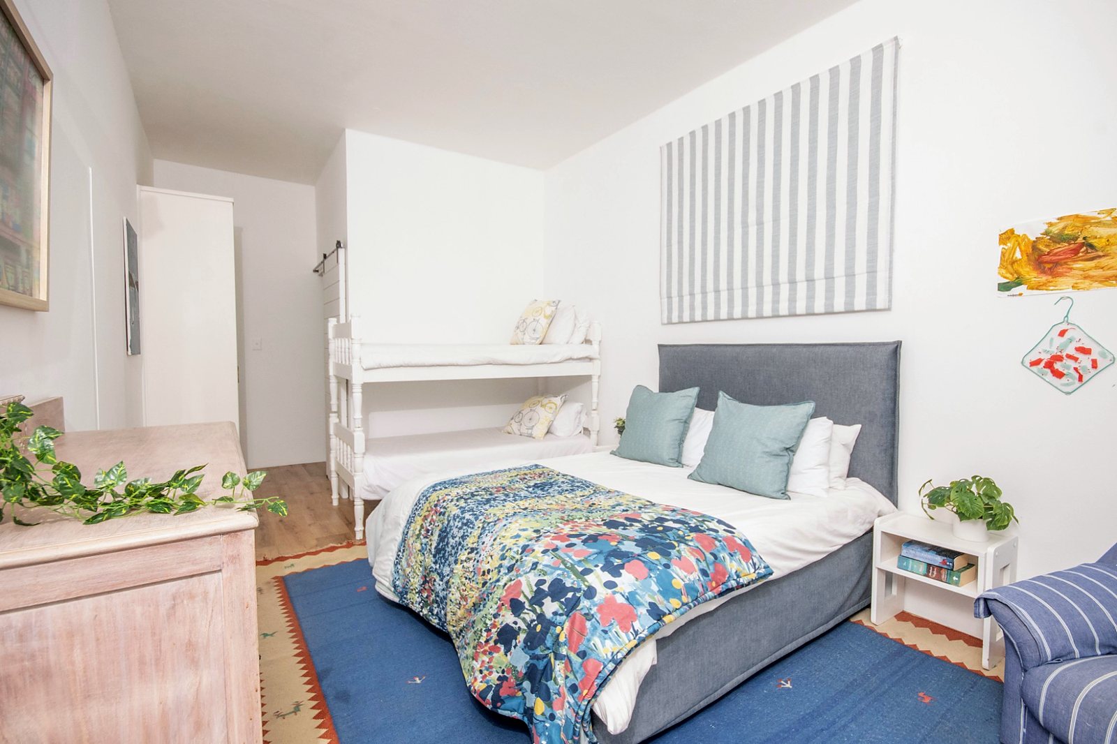 Family suite with a double bed, a floral throw and white bunk beds behind