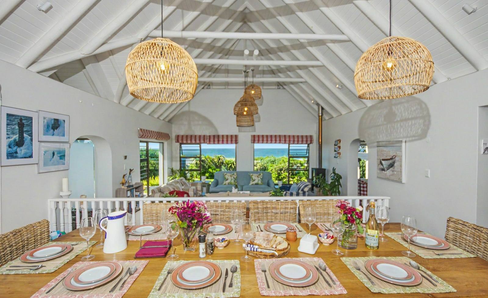 Long dining table laid for a family meal with the sea visible beyond