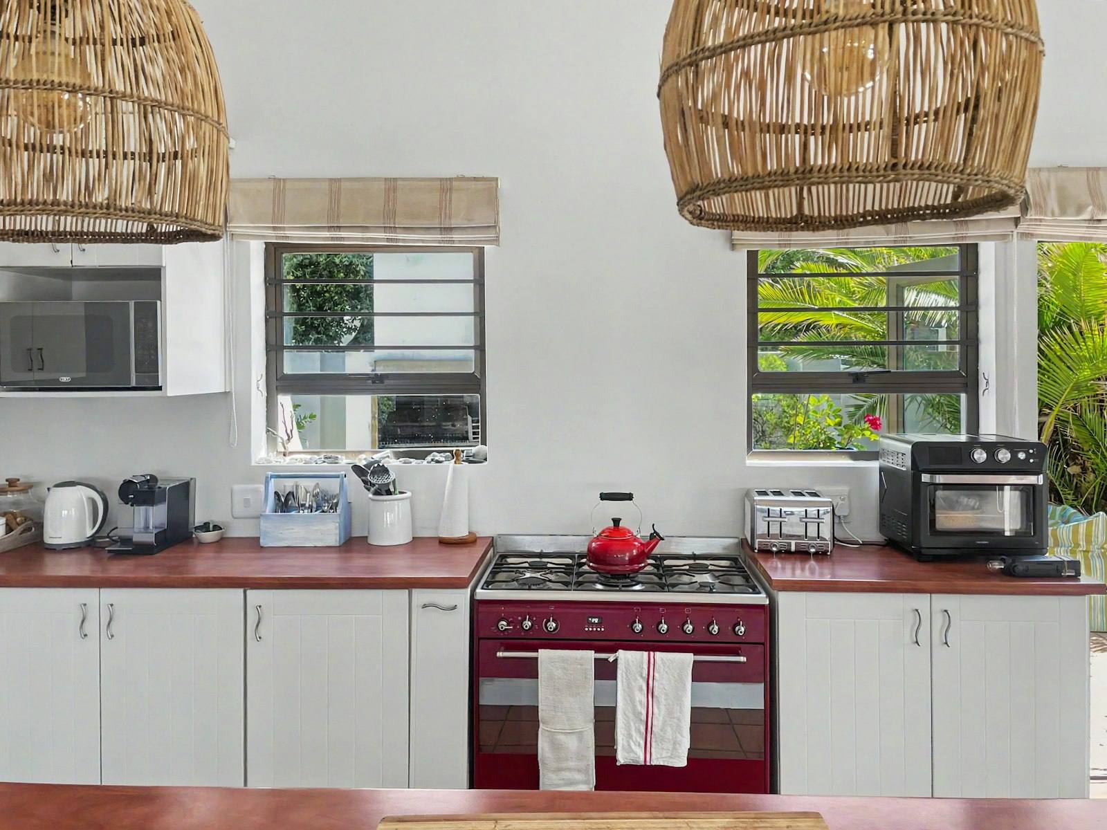 Kitchen with red SMEG range cooker and rattan pendant lights