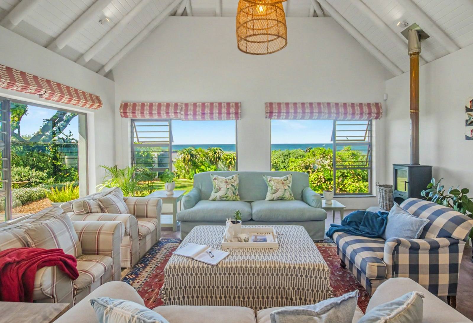 Main lounge with white beamed ceiling, gingham armchairs and sea views through three windows