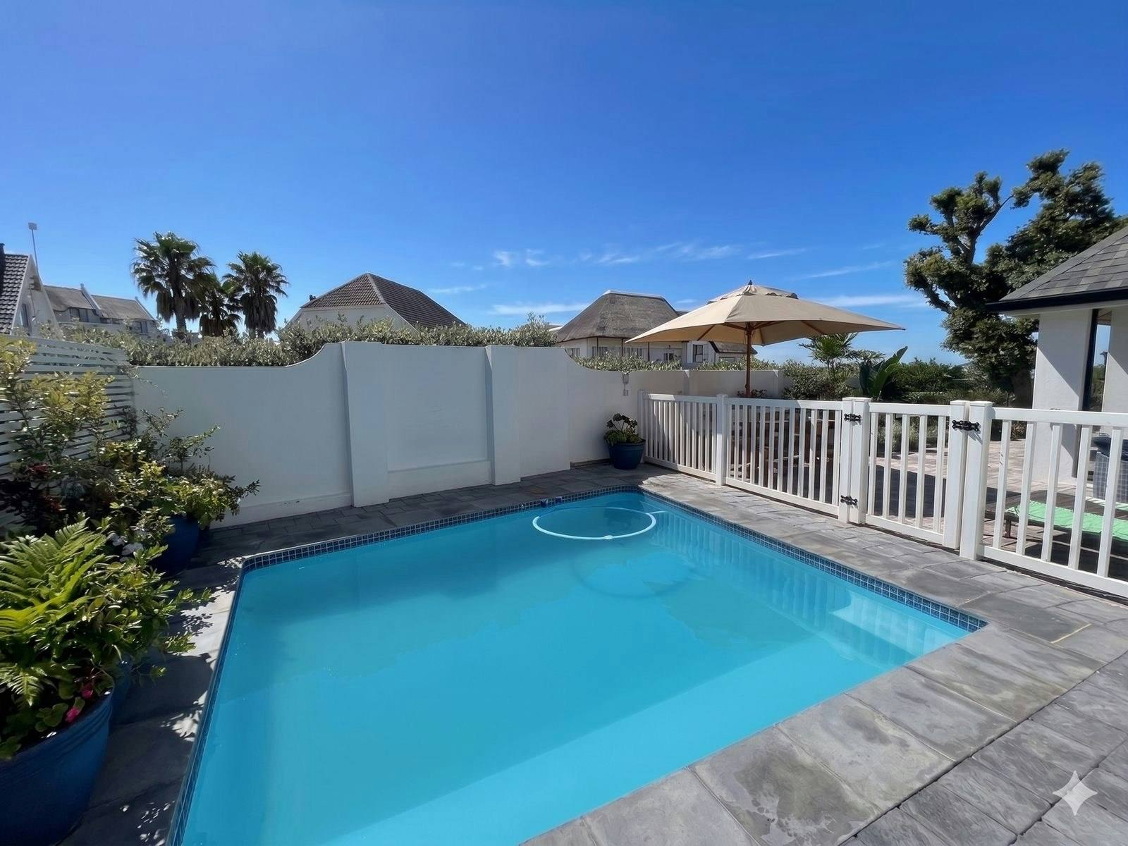 Fenced swimming pool in a sheltered white-walled courtyard